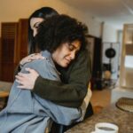 A heartfelt embrace between two women, sharing comfort and support over a cup of coffee.